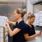 Maids working in hotel laundry room.